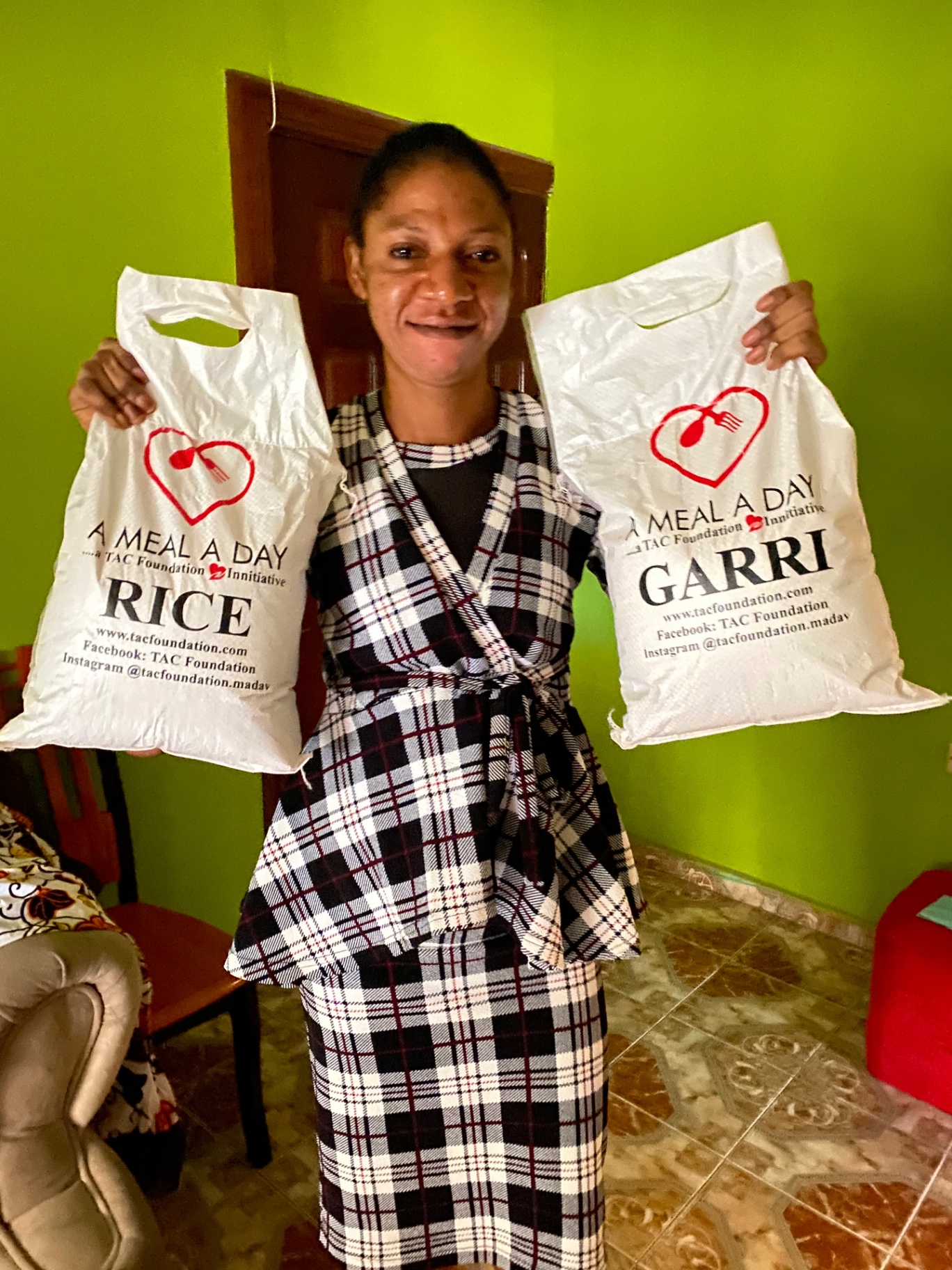 A beneficiary holding A Meal A Day rice and garri bags